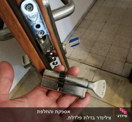 יד מחזיקה צילינדר מנעול ליד דלת עם מנעול